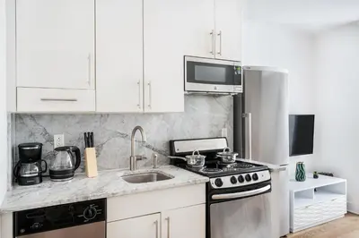 a white kitchen with a stove and a sink at 1 BR Gem in Prime Location of NYC in New York