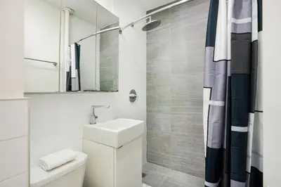 a white bathroom with a sink and a mirror at 1 BR Gem in Prime Location of NYC in New York