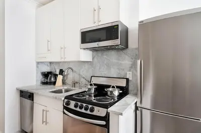 a kitchen with a stove and a stainless steel refrigerator at 1 BR Gem in Prime Location of NYC in New York