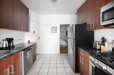 a kitchen with wooden cabinets and a black refrigerator at Prime Upper west Side Location 1 Bedroom Apt in New York