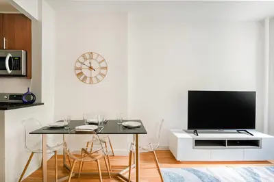 a living room with a table and a tv on a wall at Prime Upper west Side Location 1 Bedroom Apt in New York