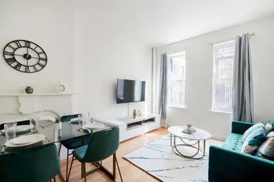 a living room with a table and chairs and a clock at Contemporary 1 Bedroom Apartment in NYC in New York