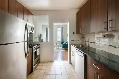 a kitchen with wooden cabinets and a stainless steel refrigerator at Contemporary 1 Bedroom Apartment in NYC in New York