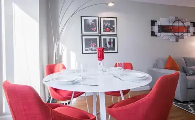 a dining room with a white table and red chairs at Fully Furnished Studio Apartment in New York