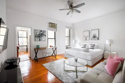 a white living room with a bed and a couch at Bright and Comfy Studio in NYC in New York