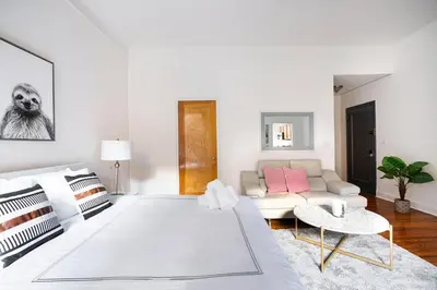 a white living room with a couch and a table at Bright and Comfy Studio in NYC in New York
