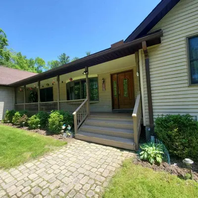 a house with a front porch with a wooden door at Spacious House with a Pool in Glen Spey