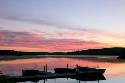 two boats docked at a dock on a lake at sunset at Inn at Lake Joseph in Forestburgh