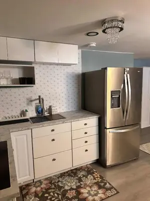 a kitchen with white cabinets and a stainless steel refrigerator at Suhira Hospitality in Lansdowne