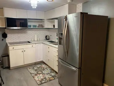 a kitchen with a stainless steel refrigerator and white cabinets at Suhira Hospitality in Lansdowne