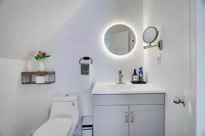a white bathroom with a toilet and a mirror at Remodeled 4BR w Yard, Fire Pit, Near Camelback in Tannersville