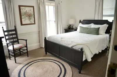 a bedroom with a bed with a chair and a window at Strasburg Village Inn in Strasburg