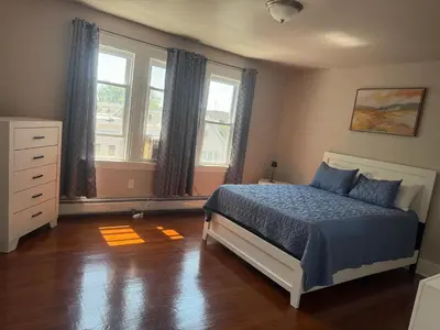 a bedroom with a bed and a dresser and two windows at Judees' Comfort 3 in Newark