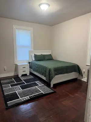 a bedroom with a bed with a green bedspread and a window at Judees' Comfort 3 in Newark