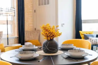 a table with plates and a vase with flowers on it at Bright & Bold+NYC View, Sleep 13, Park 2 cars FREE in East Orange