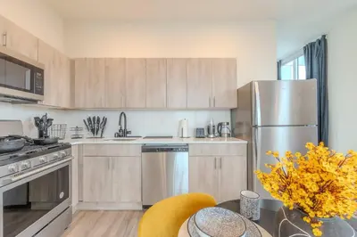 a kitchen with wooden cabinets and a stainless steel refrigerator at Bright & Bold+NYC View, Sleep 13, Park 2 cars FREE in East Orange