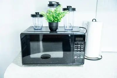 a black microwave with a plant on top of it at The Cozy Grey Haven Home - 1st floor in Reading