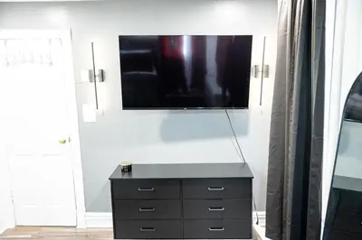 a room with a dresser and a television on a wall at The Cozy Grey Haven Home - 1st floor in Reading
