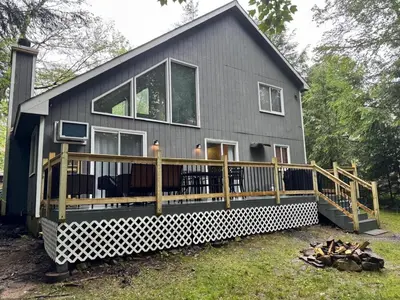 a large house with a large deck in front of it at Cozy Retreat in Scenic Poconos in Tobyhanna