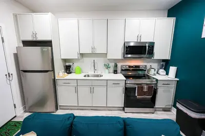 a kitchen with white cabinets and a blue wall at Perch in Paradise EaglesThemed Escape in Philadelphia