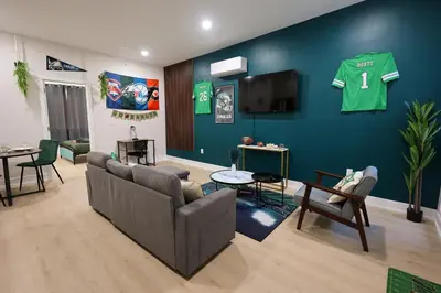 a living room with a couch and a wall with a jersey at Fly Eagles Fly StayPhilly Adventure in Philadelphia