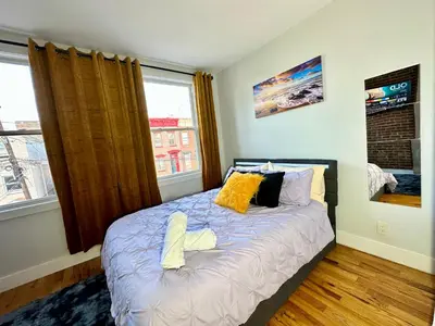 a bedroom with a bed with yellow pillows and a window at BP STAYS - Hotel-Style, No Host, Professionally Managed ID265 in Jersey City