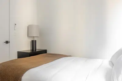 a white bed with a lamp on a night stand at Blueground Chinatown washer nr City Hall NYC-1871 in New York