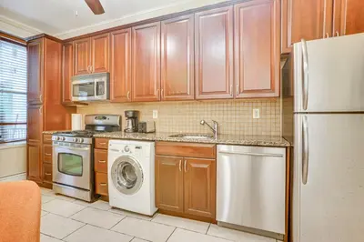 a kitchen with wooden cabinets and a washer and dryer at Walk to Washington St Hoboken Apt with Balcony! in Hoboken