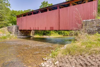 a red bridge over a river with a creek at Honey Bee Farm On-Site Susquehanna Valley Apt! in Dalmatia