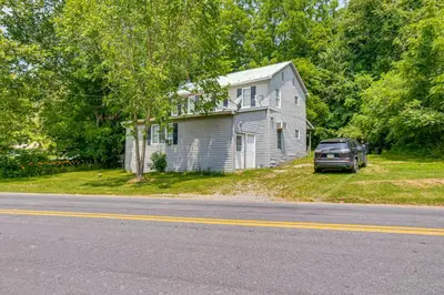 a house and a car parked in front of a road at Honey Bee Farm On-Site Susquehanna Valley Apt! in Dalmatia