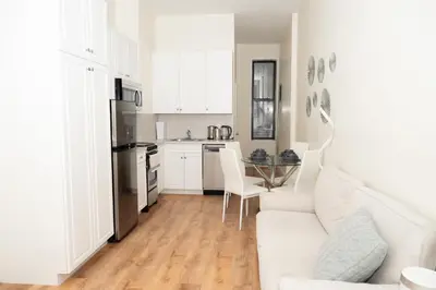 a white living room with a white couch and a kitchen at East2 Village Center Apartment7 w Full Amenities Great New York Location in New York