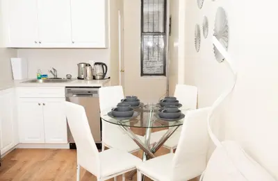 a dining room with a glass table and white chairs at East2 Village Center Apartment7 w Full Amenities Great New York Location in New York