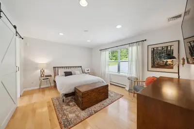 a white bedroom with a bed and a table at Stylish Catskills Escape Near Town & Trails in Livingston Manor