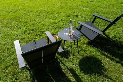 a table and chairs in the grass with a bottle on it at Stylish Catskills Escape Near Town & Trails in Livingston Manor