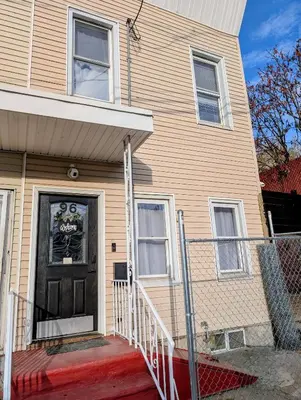 a house with a black door with a sign on it at Newly Renovated Charming Apt! 30 Mins to Manhattan in Jersey City