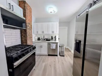 a kitchen with white cabinets and a stainless steel refrigerator at Newly Renovated Charming Apt! 30 Mins to Manhattan in Jersey City