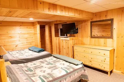a bedroom with two beds and a television in a cabin at 6 BR log cabin JFBB ski /HOT TUB in Blakeslee