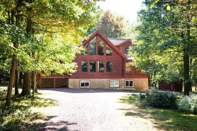 a large wooden house with a driveway in front of it at 6 BR log cabin JFBB ski /HOT TUB in Blakeslee