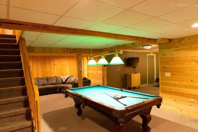 a living room with a pool table and stairs at 6 BR log cabin JFBB ski /HOT TUB in Blakeslee