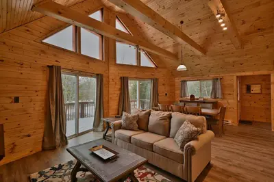 a living room with a couch and a table at NEW ! Lake front Lookout Log Cabin! Private Lake ! in White Haven