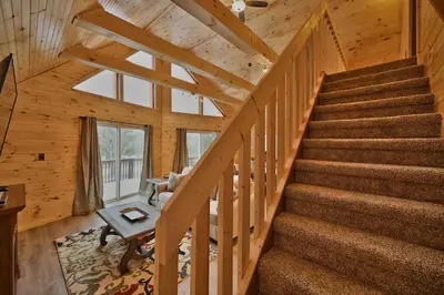 a staircase in a log cabin with a table and a chair at NEW ! Lake front Lookout Log Cabin! Private Lake ! in White Haven