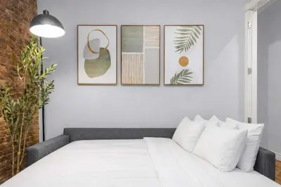 a bedroom with a white bed with four pictures on the wall at Bold Manhattan Base in Prime Nolita in New York