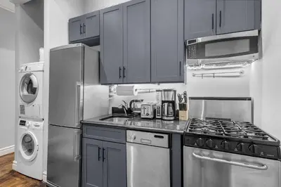 a kitchen with stainless steel appliances and a washer and dryer at Bold Manhattan Base in Prime Nolita in New York