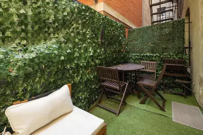 an ivy covered wall with two chairs and a table at Modern Nolita Hideaway in New York