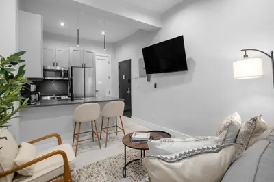 a living room with a couch and a kitchen at Modern Nolita Hideaway in New York