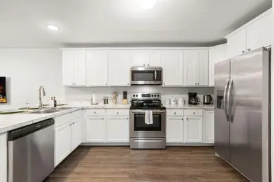 a kitchen with white cabinets and stainless steel appliances at Traveler Haven XL NYC & NWK with free parking in Newark
