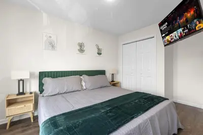 a bedroom with a bed with a green headboard at Traveler Haven XL NYC & NWK with free parking in Newark