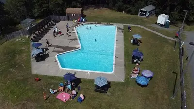 an overhead view of a swimming pool with people sitting under umbrellas at Pocono Chalet with Sauna/Hot Tub/Firepit/10+ Beds in Long Pond