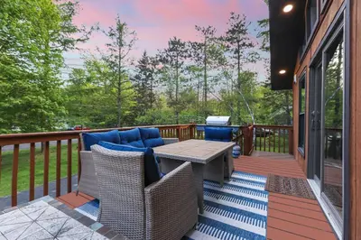 a patio with a table and chairs on a deck at Pocono Chalet with Sauna/Hot Tub/Firepit/10+ Beds in Long Pond