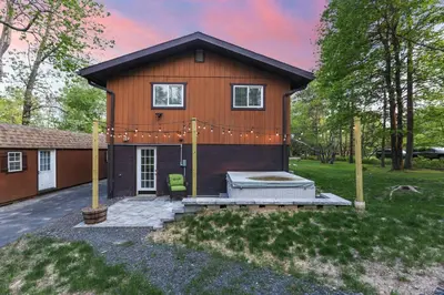 a tiny house with a porch and a backyard at Pocono Chalet with Sauna/Hot Tub/Firepit/10+ Beds in Long Pond